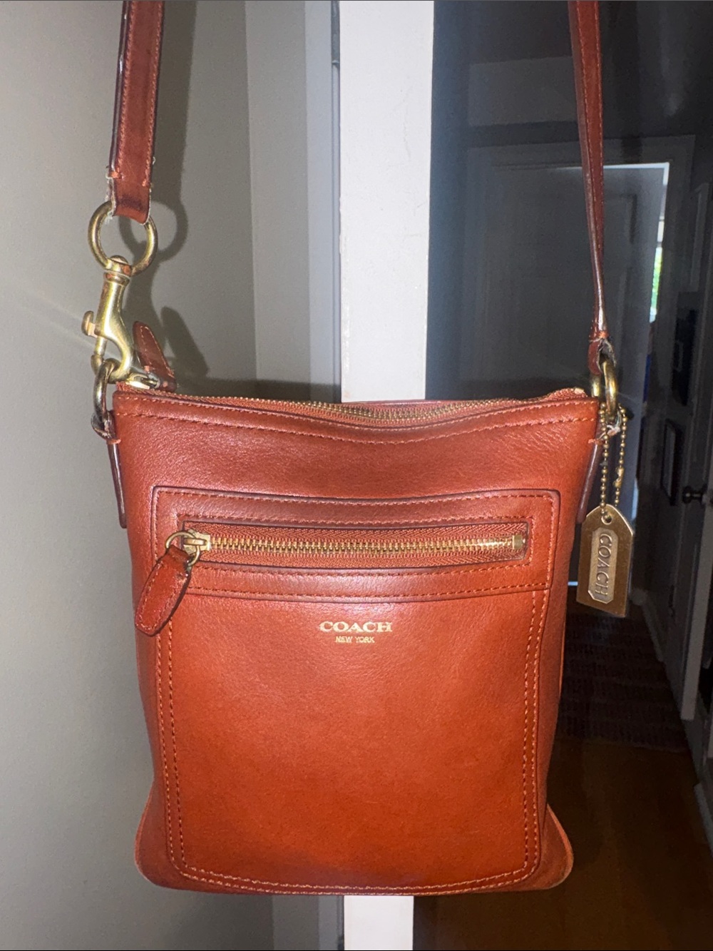 Coach Legacy Leather Swingpack Crossbody in Brown with gold hand tag.